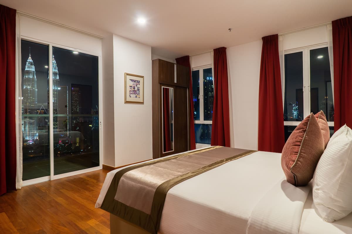 Een hotelkamer met een bed, een schuifglazen deur naar een balkon en uitzicht op de stad.