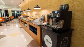 A coffee station with a coffee machine, a water dispenser, and a food display.