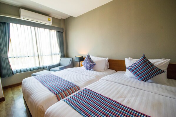 Habitación de hotel con dos camas, un escritorio y un equipo de aire acondicionado.