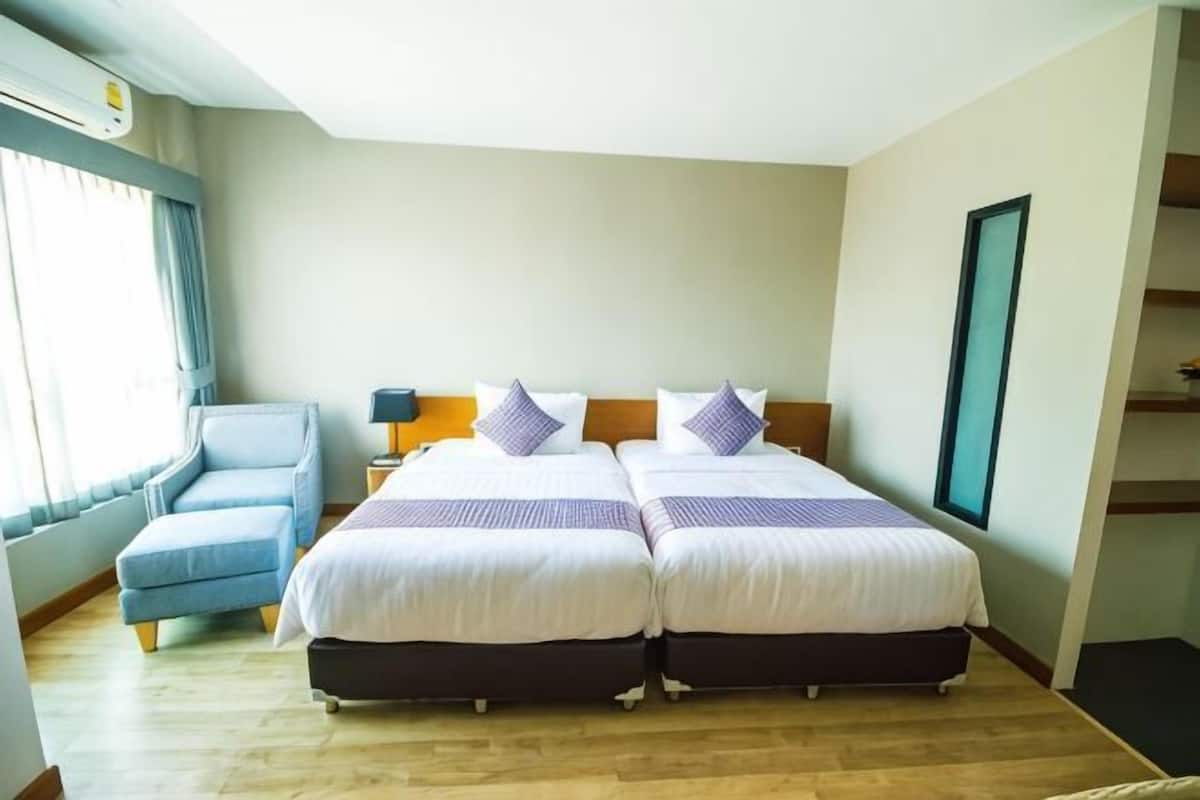 A hotel room with two beds, a sofa, a nightstand, and a window with curtains.