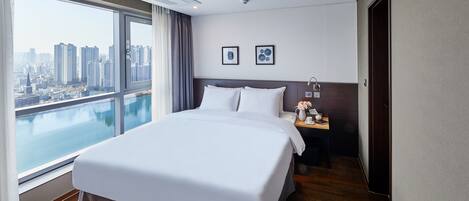 A hotel room with a large bed, a nightstand, a view of the city, and a cityscape through the window.