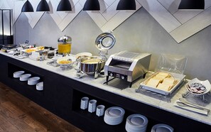 A buffet setup with various food items, a coffee machine, and a toaster.