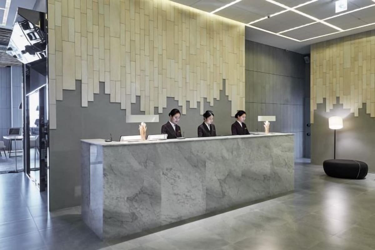 A modern reception desk with a marble counter and a geometric wall design.