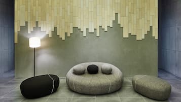 Un interior moderno con una pared texturizada, una lámpara de pie y tres sillones de felpa.