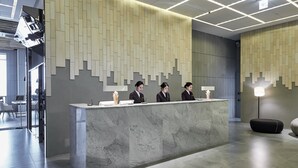 A reception desk with three staff members, a modern interior with a geometric wall design, and a clean, minimalist aesthetic. - Hotel Riverside (Ulsan)