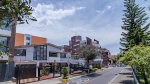 A street view with modern buildings, a bike lane, and a sidewalk with trees and plants. - Hotel Calle 112 (Bogotá)