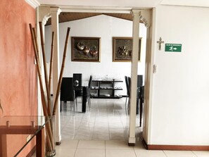A hallway with a dining area, bamboo plants, and emergency exit sign. - Hotel Calle 112 (Bogotá)