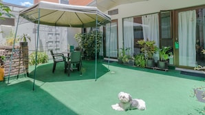 A covered patio area with artificial turf, a small table and chairs, and a dog. - Hotel Calle 112 (Bogotá)