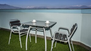 A balcony with a table and chairs, a view of distant mountains, and artificial grass. - Classic Serviced Apartments (Lalitpur)