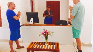 A reception area with a desk, computer, and a vase of flowers.