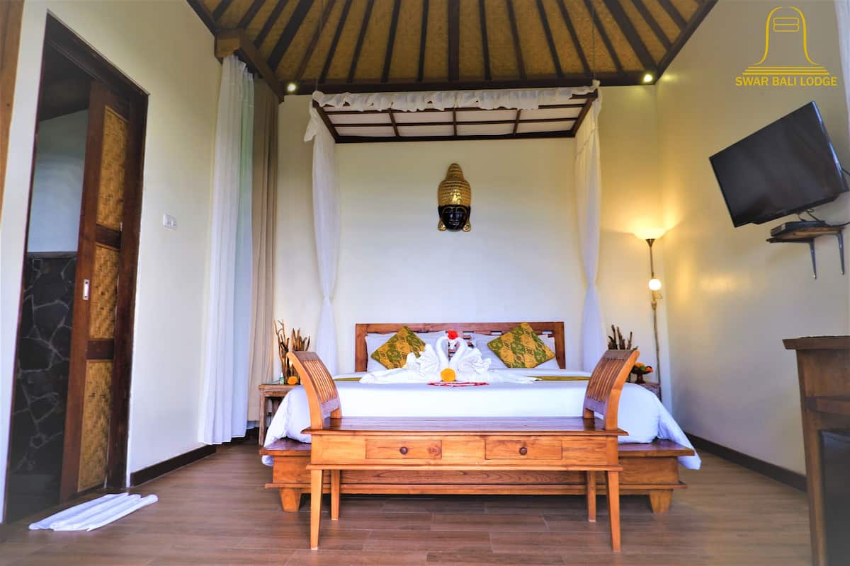 A bedroom with a wooden bed, a television mounted on the wall, and a ceiling fan.