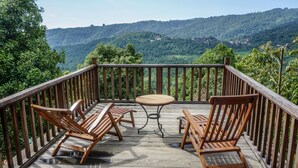 A wooden deck with a table and four chairs, overlooking a mountainous landscape. - Swar Bali Lodge (Munduk)