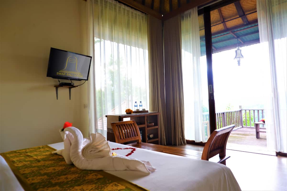 A hotel room with a bed, a TV, a desk with a chair, and a balcony with a railing.