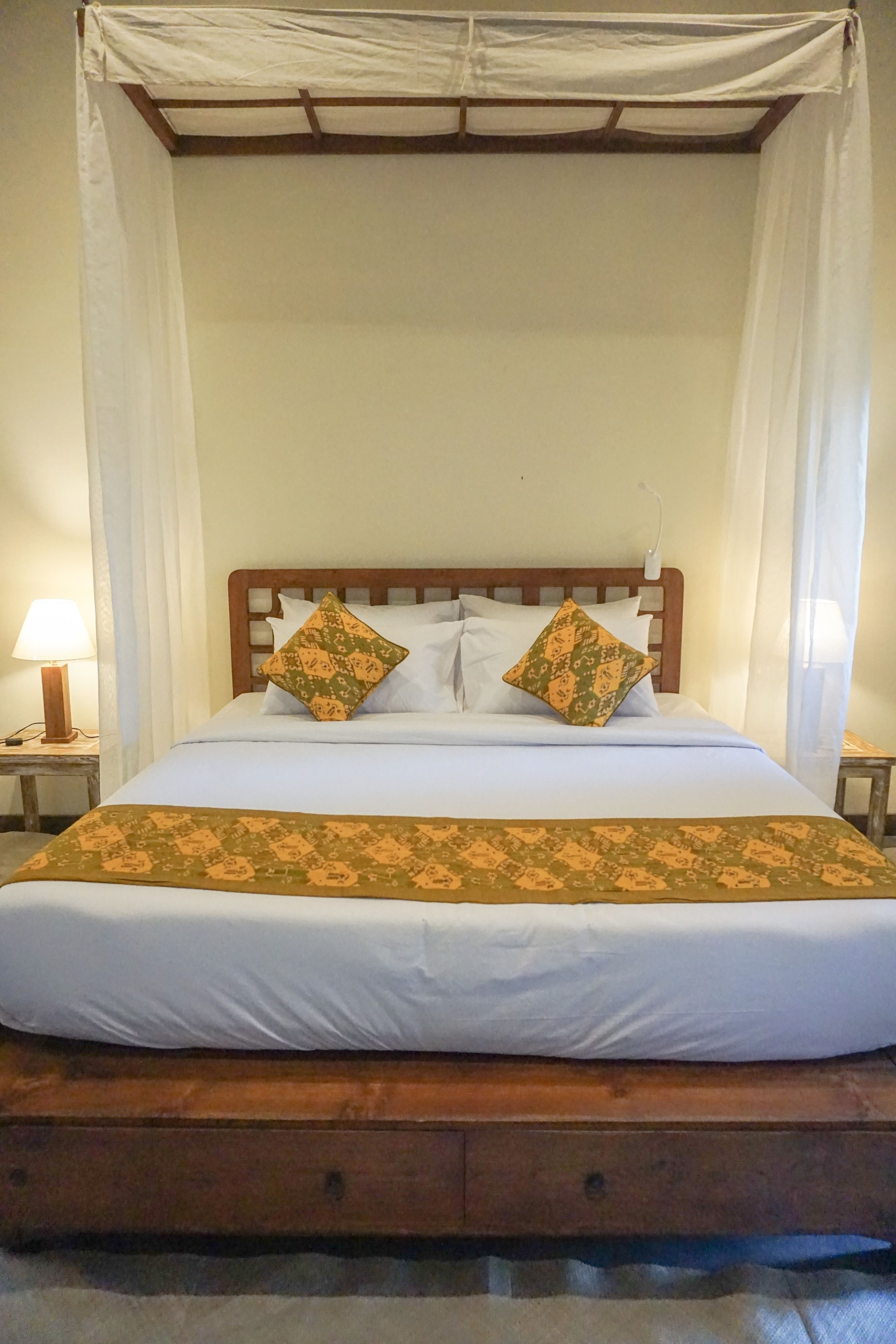 A bed with a wooden frame, white bedding, and two decorative pillows.