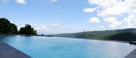 A swimming pool with a view of a forested hillside.