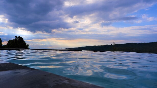 A swimming pool with a view of a cloudy sky and distant hills. - Swar Bali Lodge (Munduk)