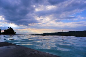 Piscina com vista para um céu nublado e colinas ao longe.