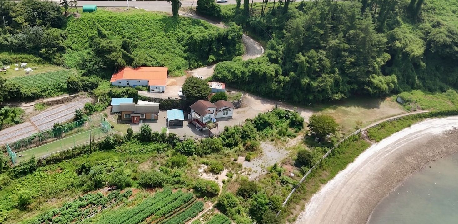 Ett flygbildsbild av ett bostadsområde med hus, en väg och en stor vattenyta.