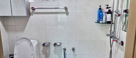 A bathroom with a toilet, a shower, and a sink.