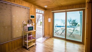 Eine Holzhütte mit einer Küchenzeile, einer großen Schiebetür zu einer Terrasse und Blick auf einen See.
