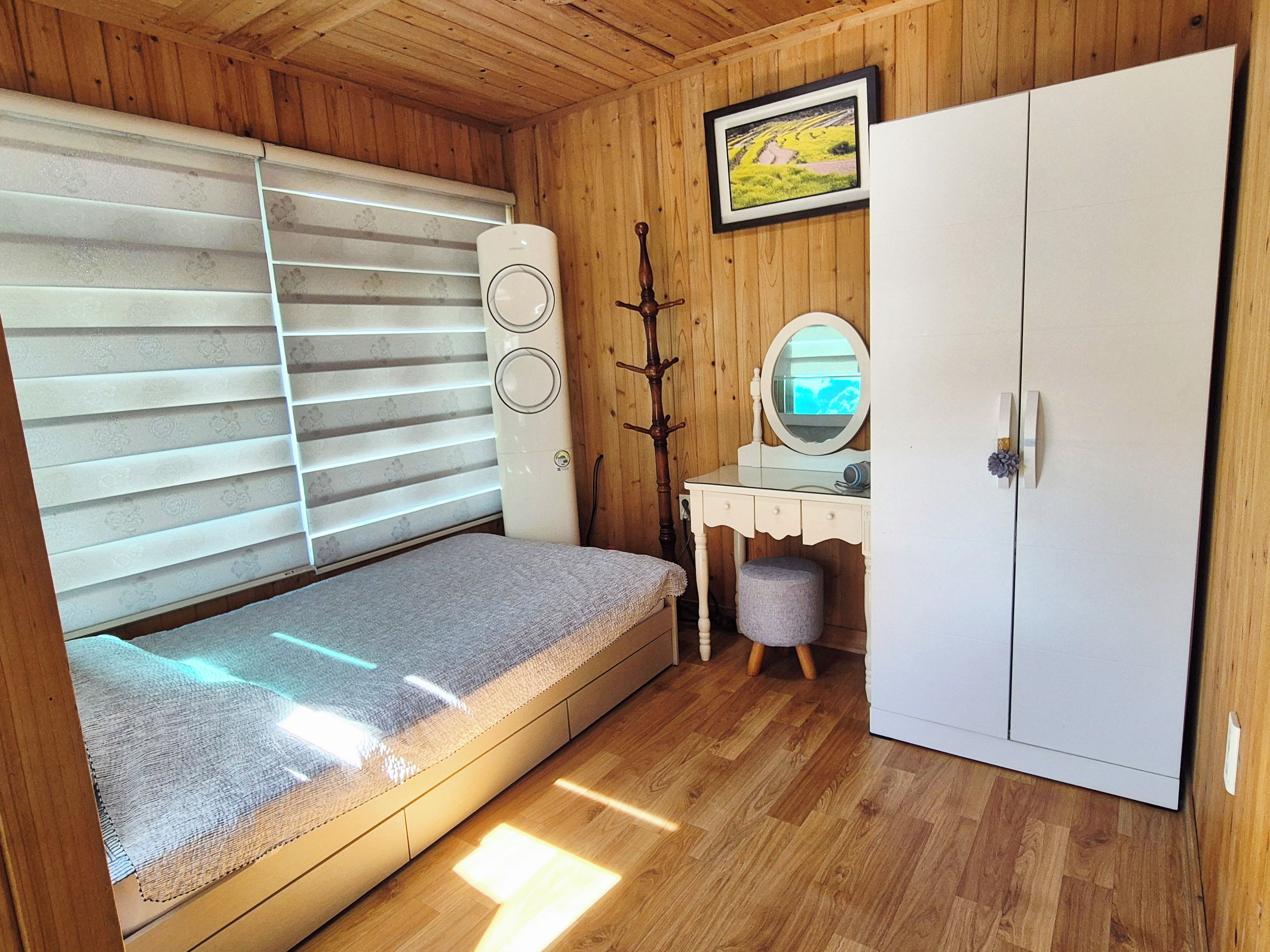 A compact room with a bed, a dresser, a mirror, and a wardrobe.
