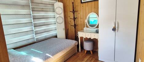 A compact room with a bed, a dresser, a mirror, and a wardrobe.