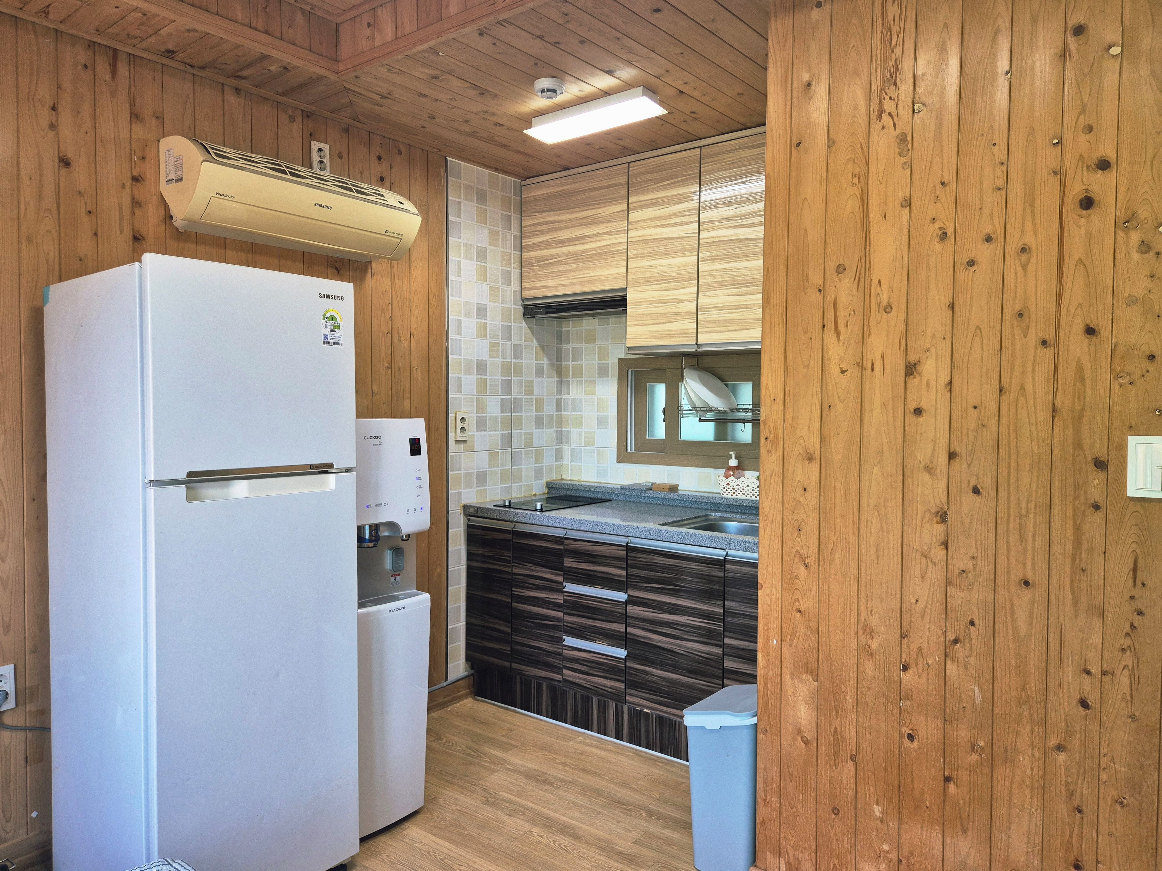 A compact kitchen with a built-in refrigerator, a water dispenser, and a dishwasher.