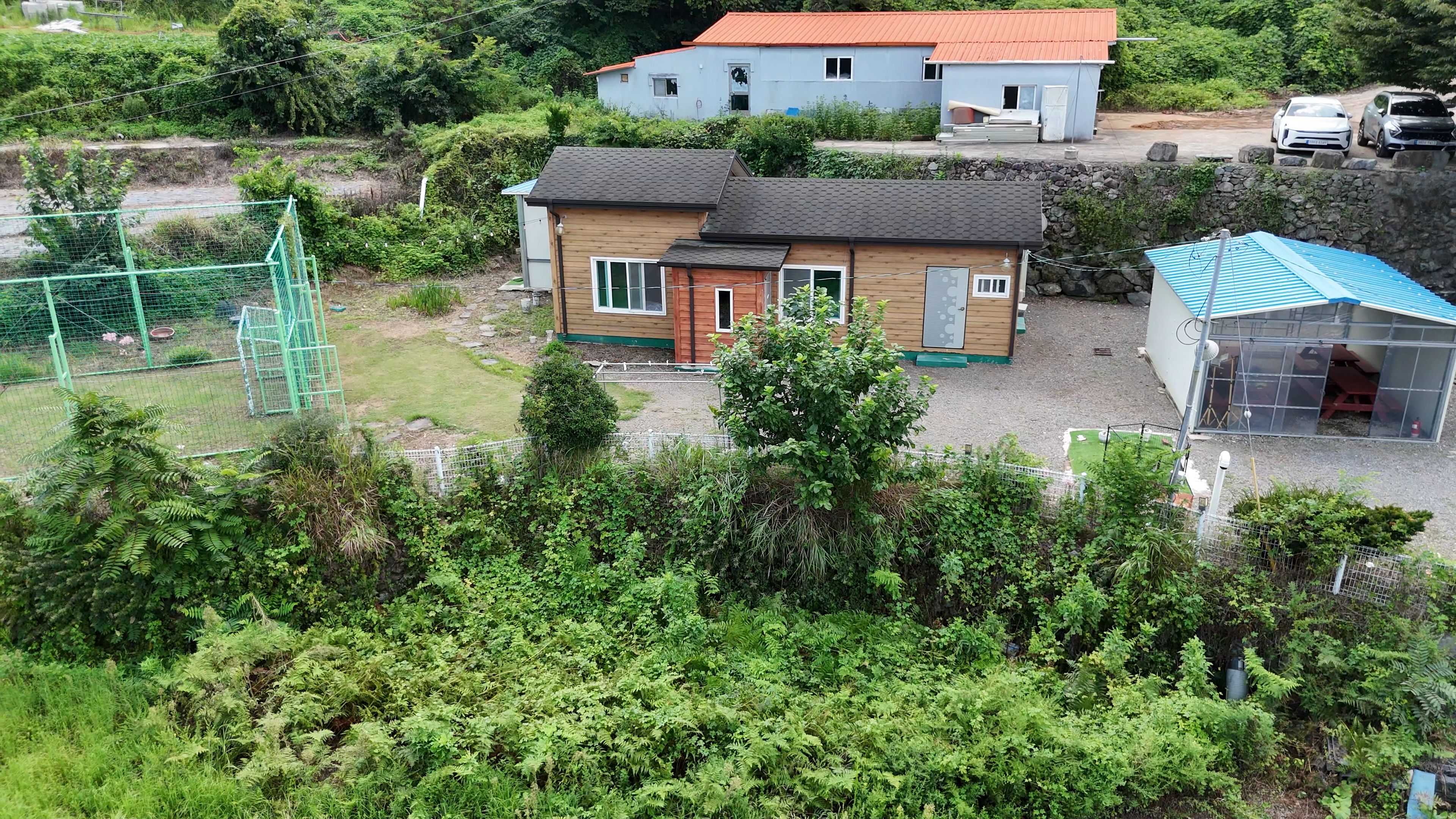 Ett bostadsområde med ett tvåvåningshus, en inhägnad trädgård och ett litet förråd.