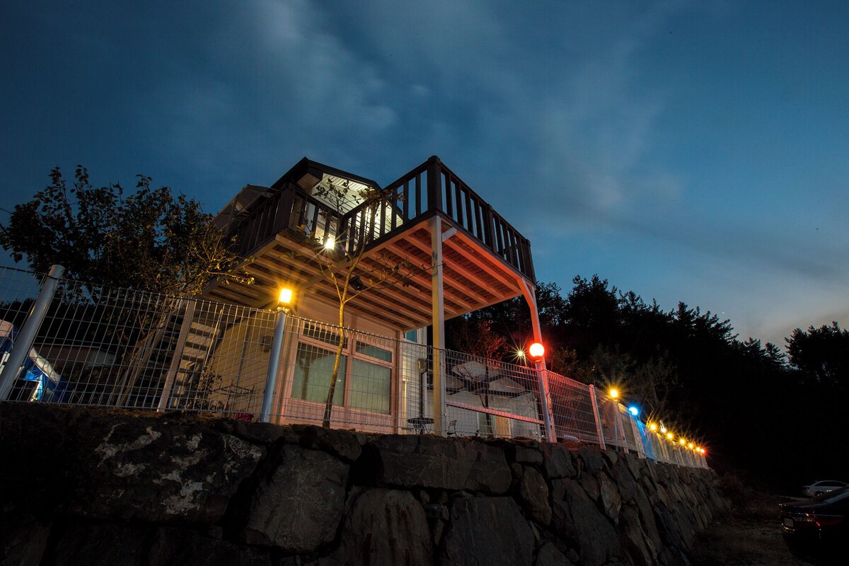 A multi-level building with a balcony, stone wall, and a fence.