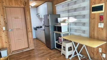A compact kitchen with a refrigerator, microwave, and a small dining table.