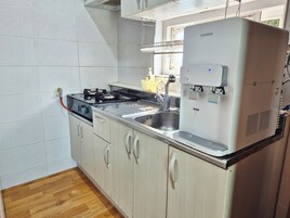 Una cocina con dispensador de agua incorporado, estufa y pileta.