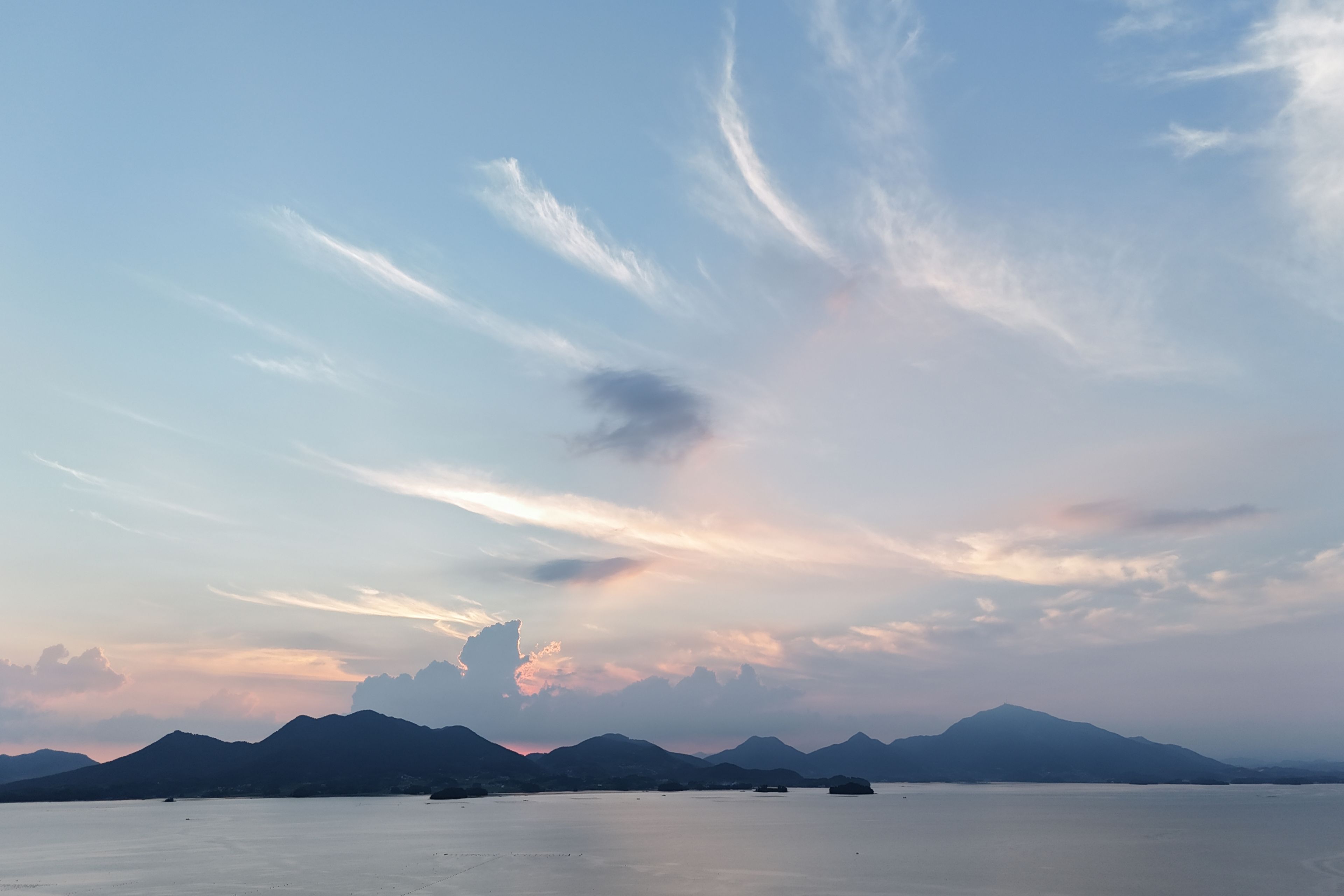 A calm body of water with distant mountains and a clear sky.
