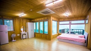 Ein Schlafzimmer mit Holzvertäfelung, einem Bett, einer Kommode, einem Spiegel, einem Ventilator und einem Kühlschrank.