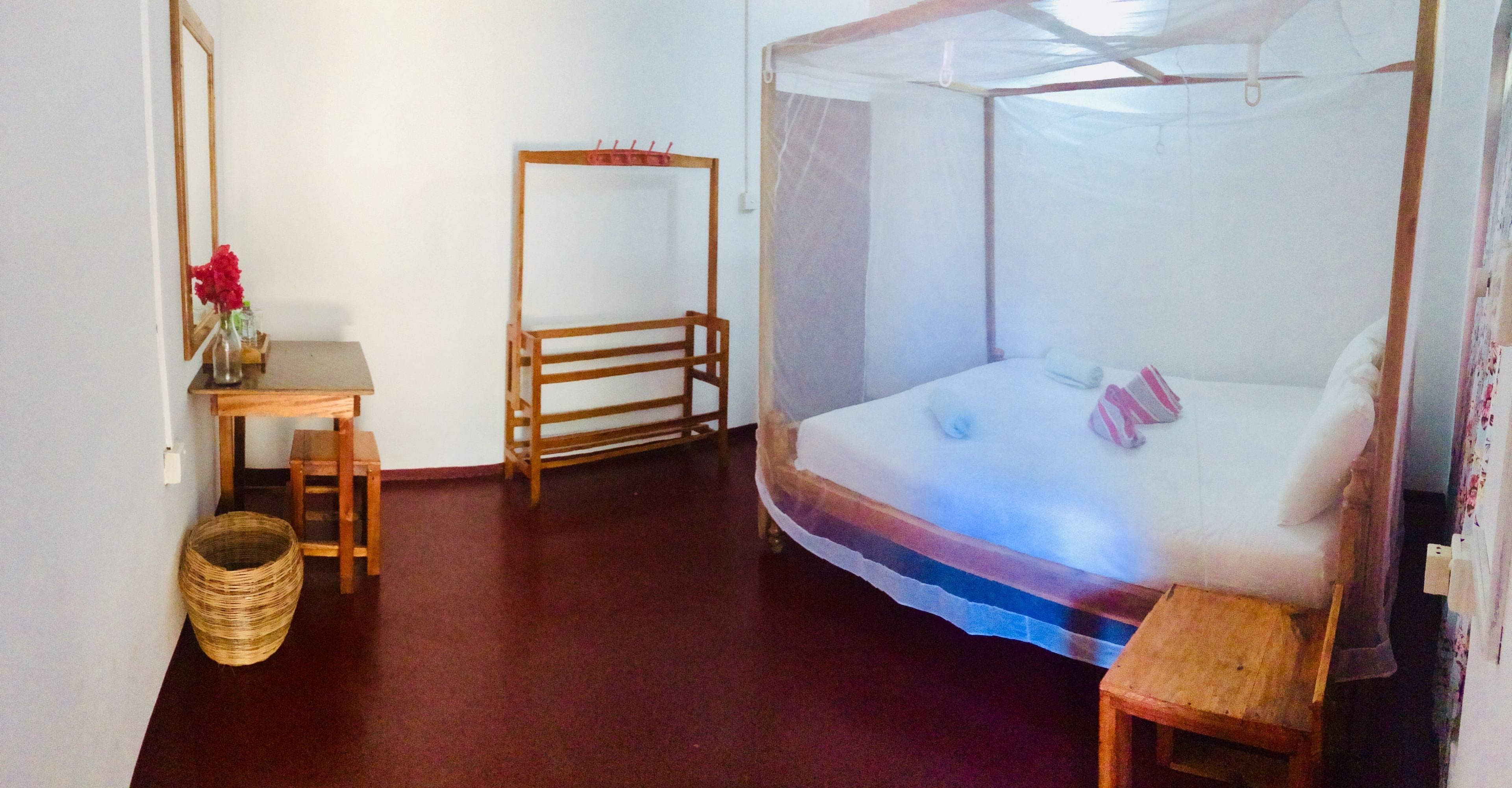 Ein Schlafzimmer mit einem Bett, einem Holzstuhl, einem kleinen Tisch und einem Moskitonetz.