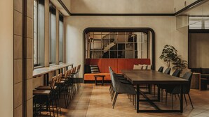 A modern meeting room with a long table, chairs, a sofa, and a staircase visible through a large window. - Nest&Rise Osaka Namba Hotel (Osaka)