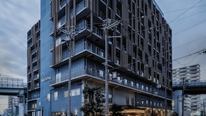 A multi-story hotel with a modern design, featuring balconies, a ground-level entrance, and a visible sign reading "Nest & Rise". - Nest&Rise Osaka Namba Hotel (Osaka)