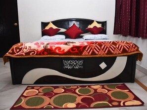 A bed with a black headboard, a patterned bedspread, and decorative pillows. - Jagannath Guest House (New Delhi)