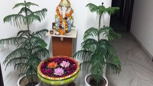 A room with a statue of a deity, a flower vase, and potted plants. - Jagannath Guest House (New Delhi)