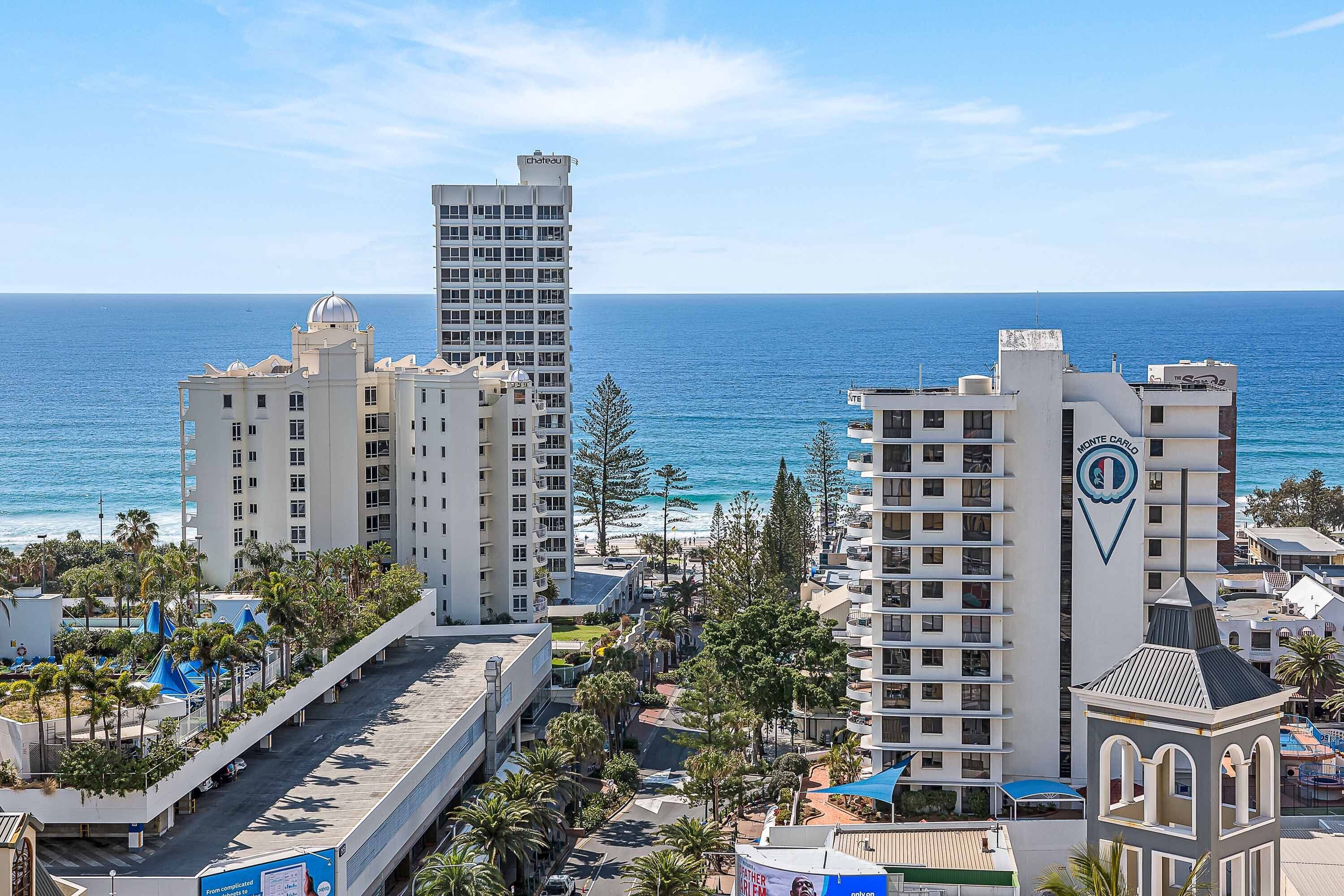A coastal hotel with multiple high-rise buildings, a beach view, and a prominent logo on one building.