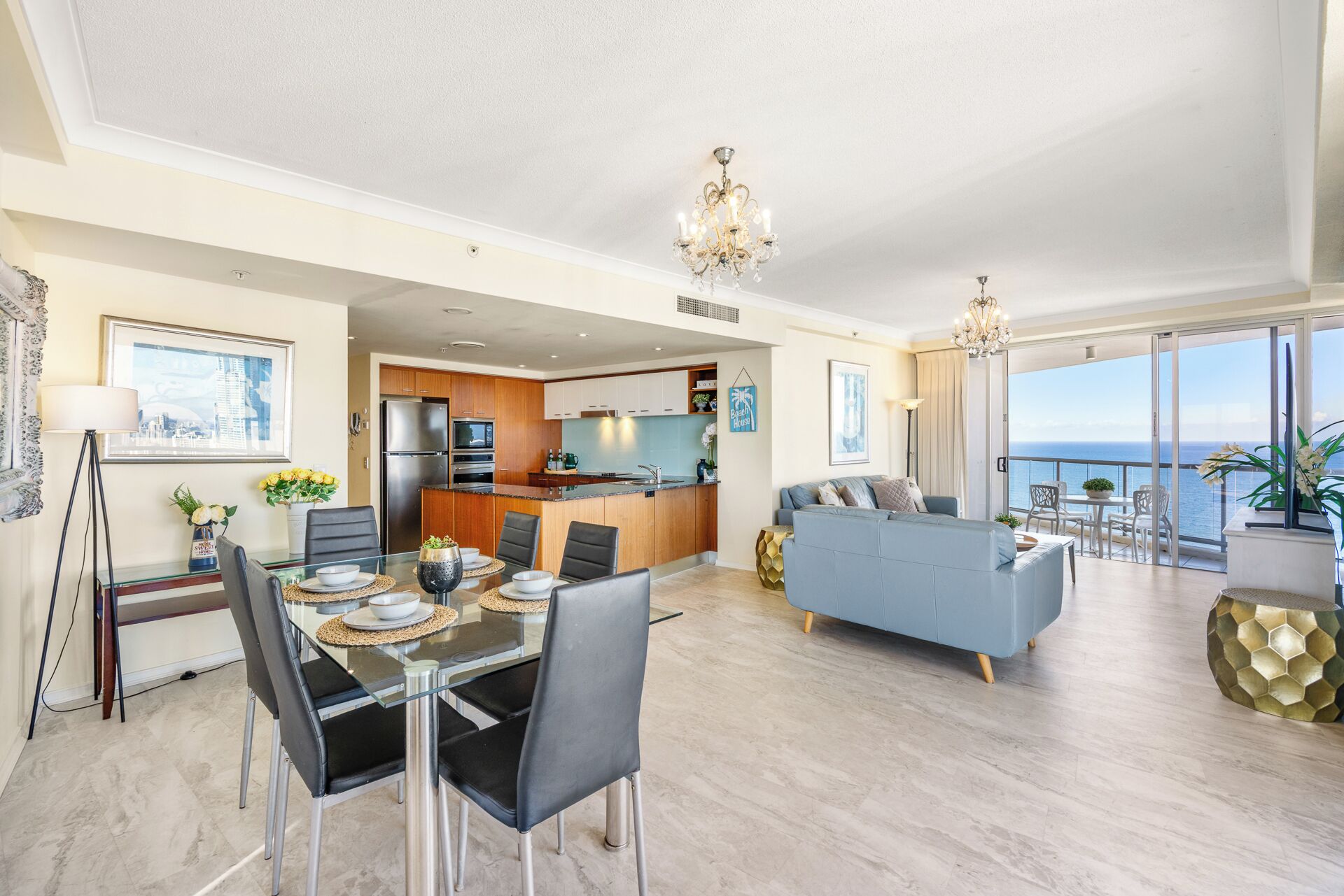 A modern living room with a dining area, kitchen, and a balcony with a view.