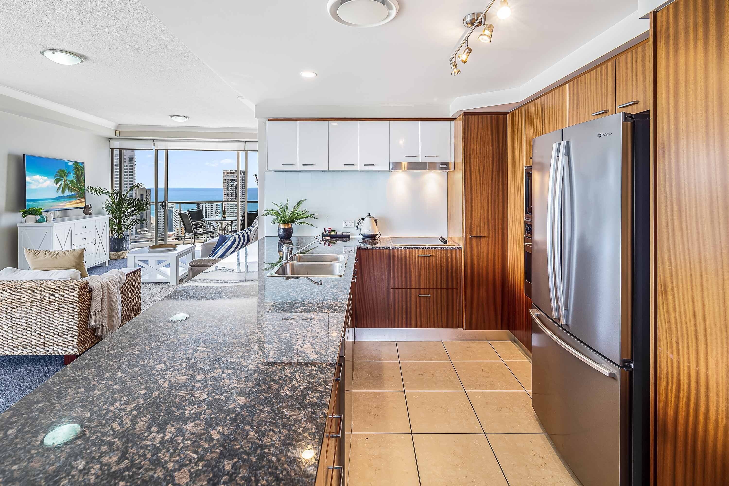 A modern kitchen with wooden cabinets, a stainless steel refrigerator, and a dining area with a glass table and chairs.