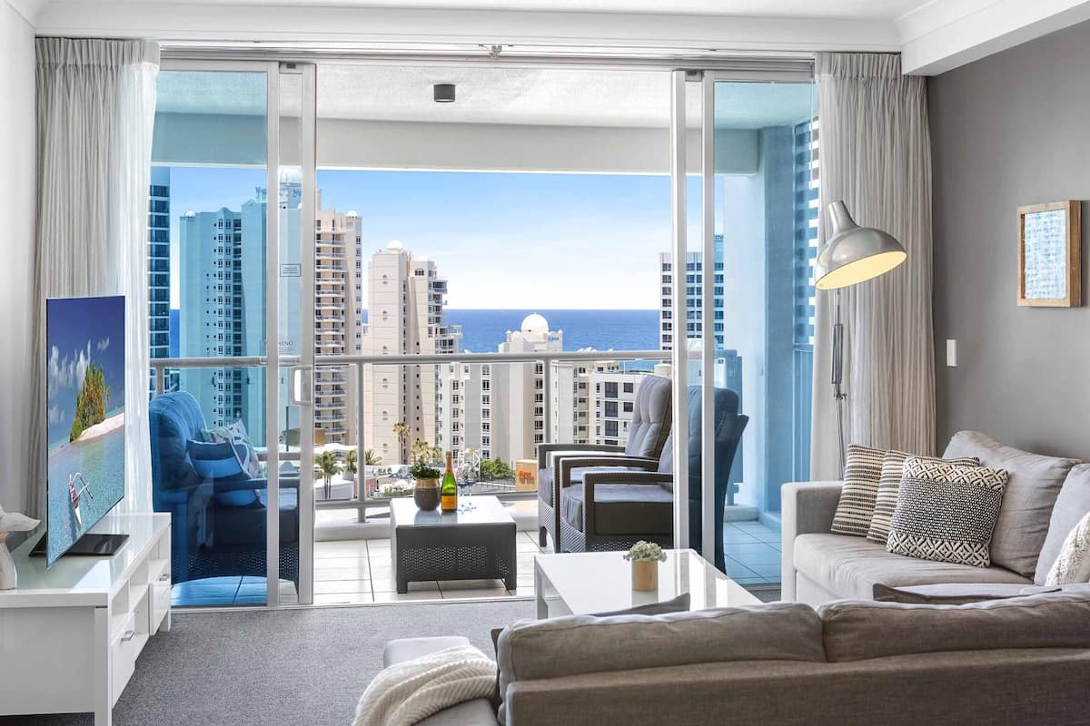 A modern living room with a balcony, furnished with a sofa, armchairs, and a coffee table.