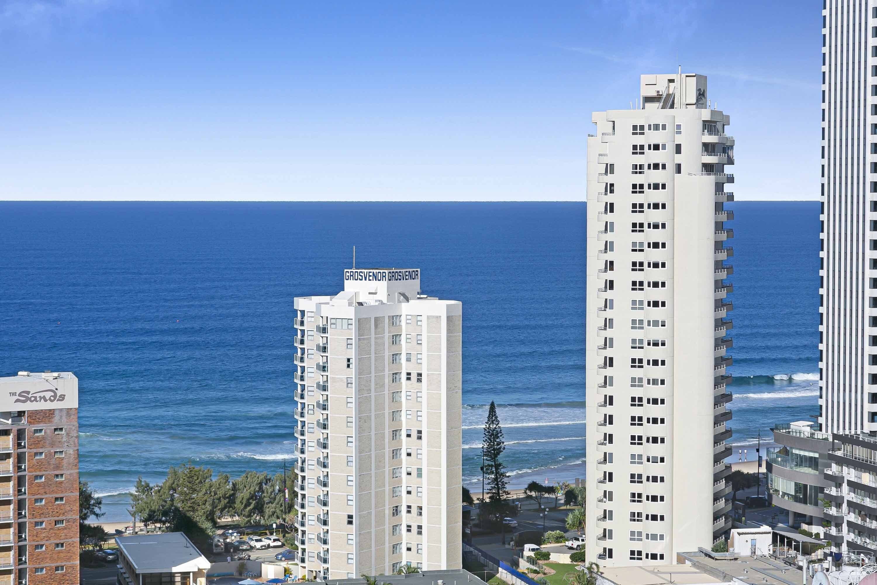 A coastal view with high-rise buildings, one labeled "Grosvenor," and a beach in the background.