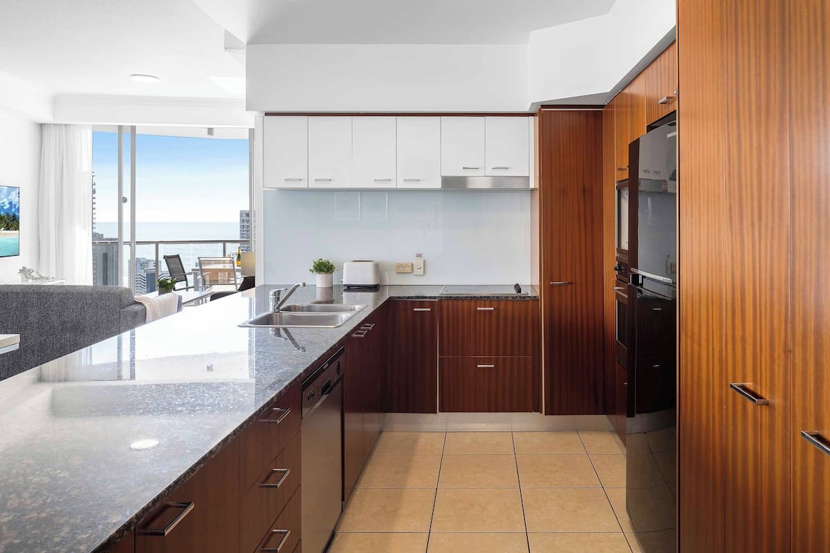 A modern kitchen with wooden cabinets, a granite countertop, and a view of the city.