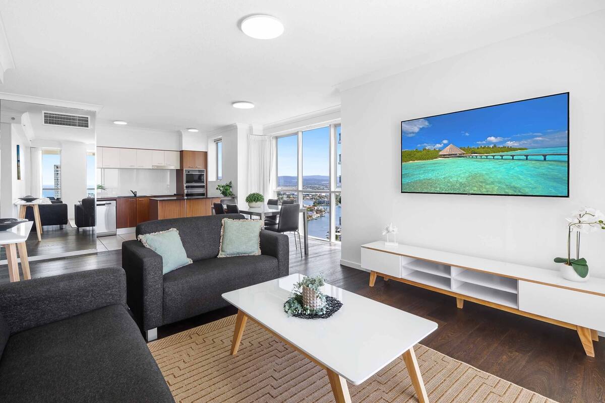 A modern living room with a sofa, coffee table, and a TV displaying a scenic view.