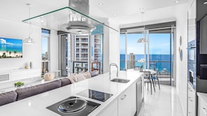 A modern kitchen with a central island, large windows, and a view of the ocean. - Holiday Holiday Chevron Renaissance (Surfers Paradise)