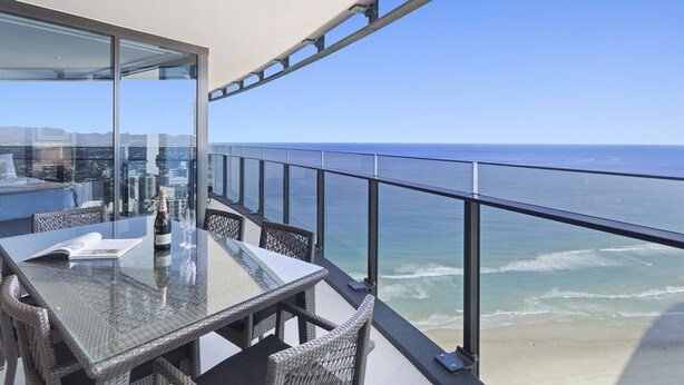 A balcony with a glass table and wicker chairs overlooking the ocean. - Holiday Holiday Soul Surfers Paradise (Surfers Paradise)