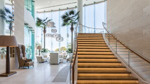 A modern hotel lobby with a curved staircase, seating area, and large windows. - Holiday Holiday Soul Surfers Paradise (Surfers Paradise)