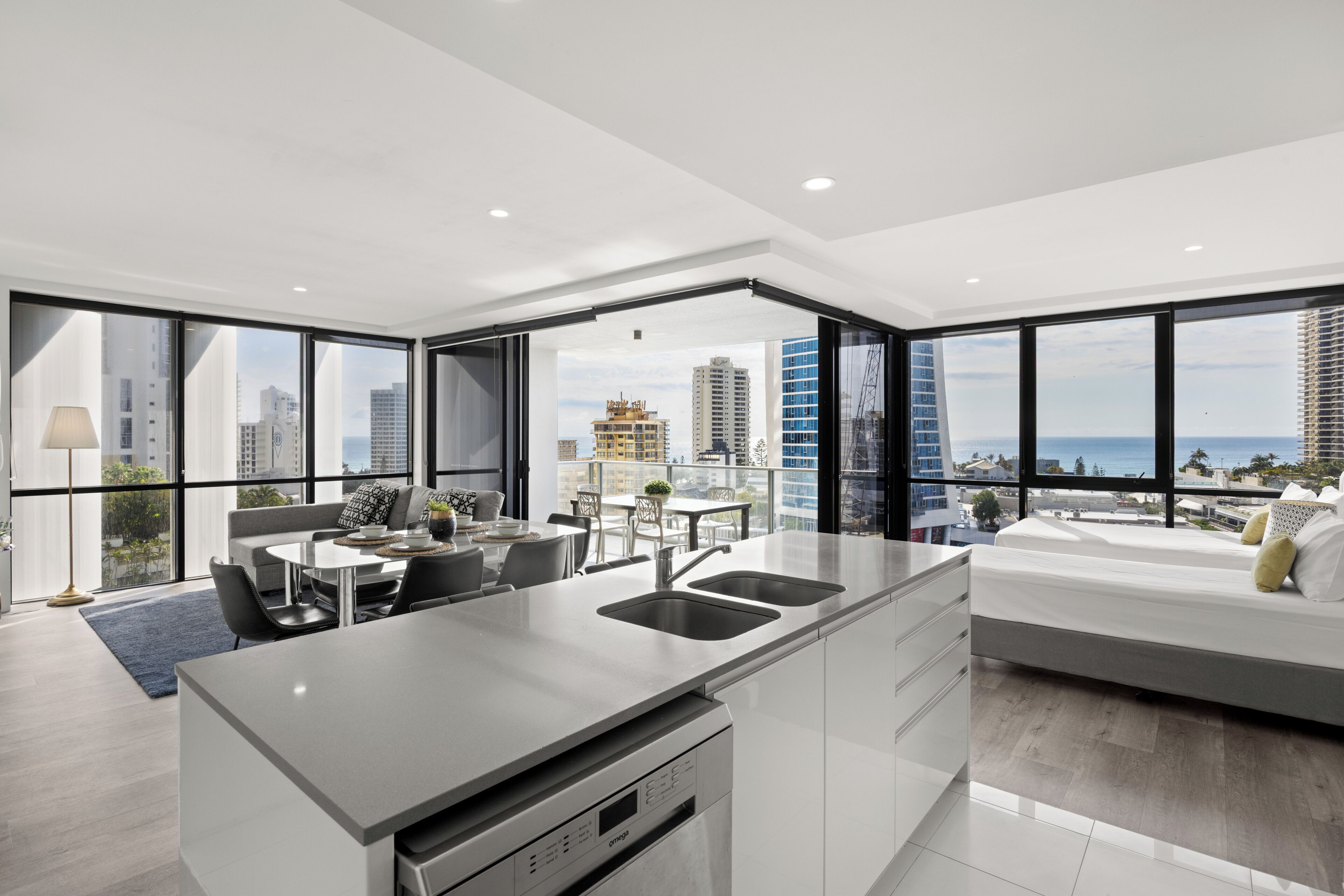 Een modern appartement met keuken, eethoek en een slaapkamer met uitzicht op de stad.