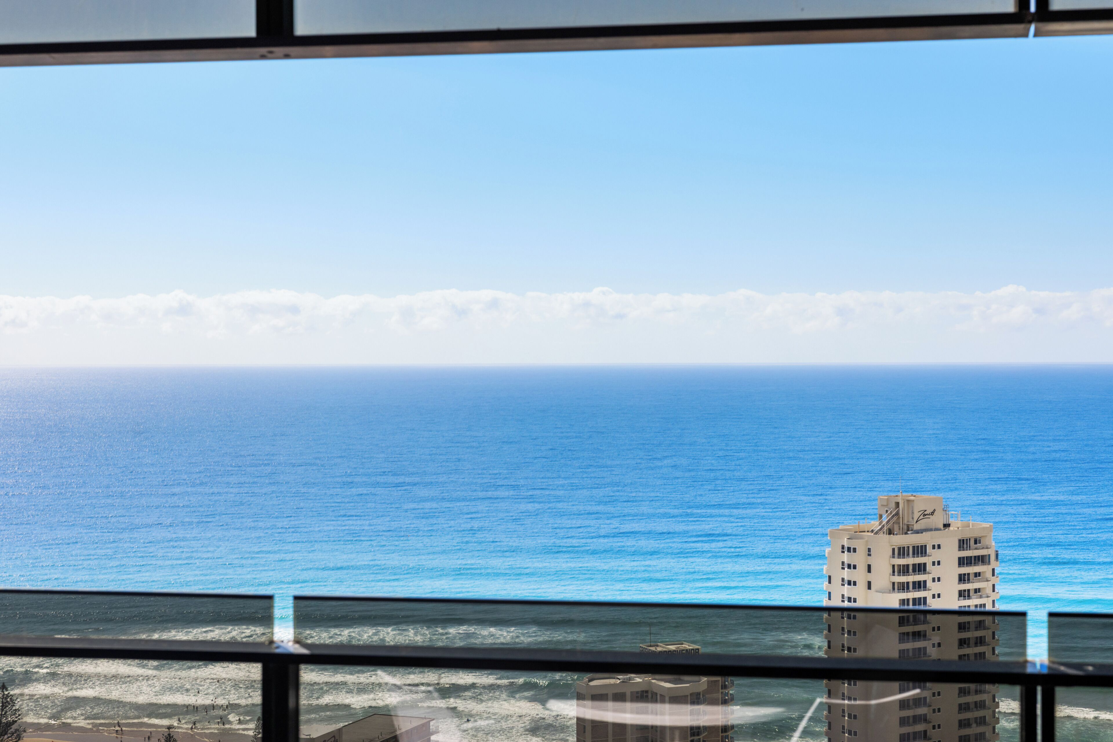 Blick auf das Meer vom Fenster aus, mit einem Gebäude im Vordergrund.